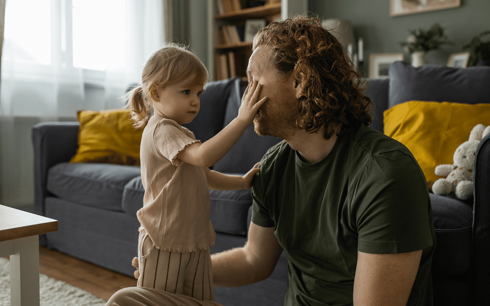 A little girl gently touching a man's face indoors.