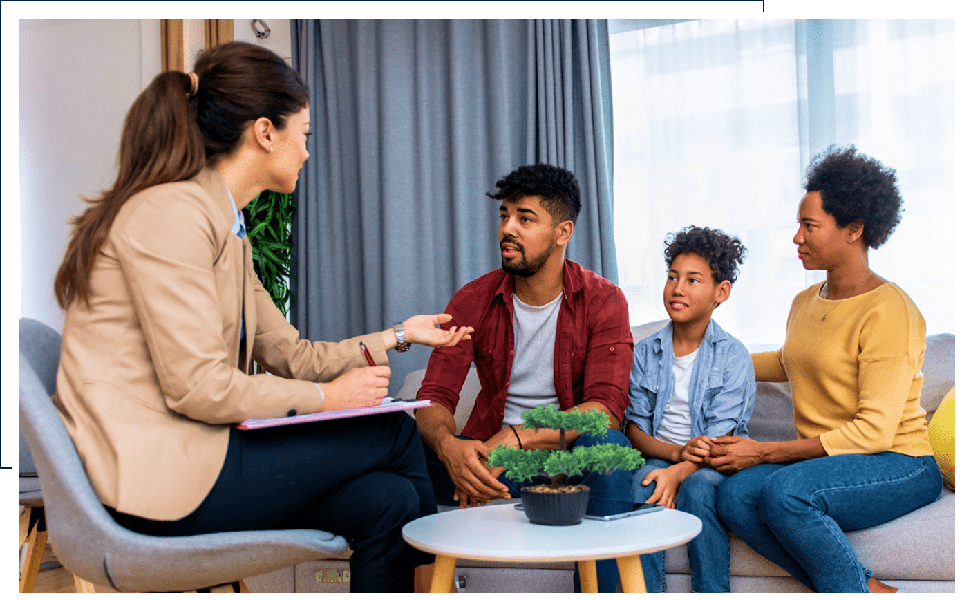 Therapist talking to a father and son during a counseling session.