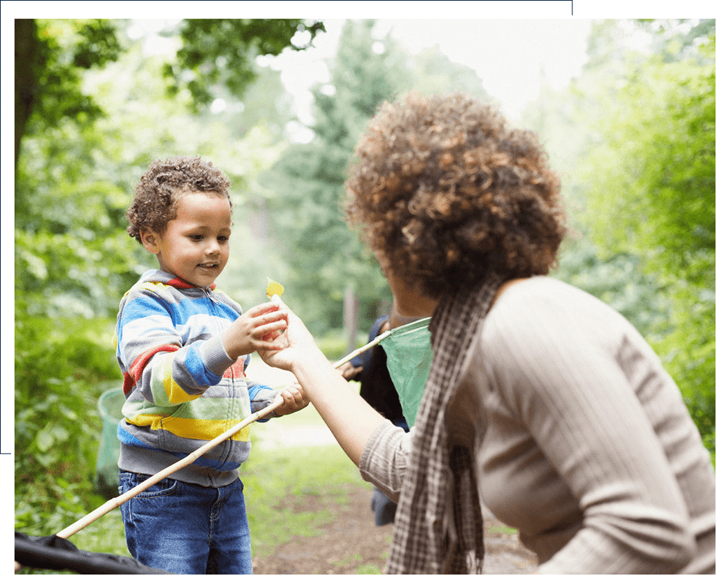 A mother and child enjoying a playful moment outdoors with sticks.
